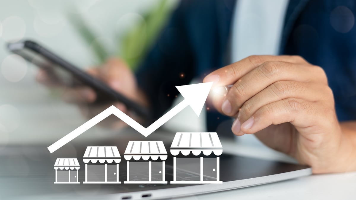 Hand using smartphone with increasing store graph icons