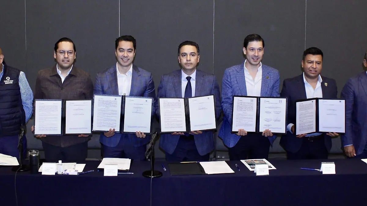 Five men in business suits holding certificates at a table during a formal signing ceremony or agreement event