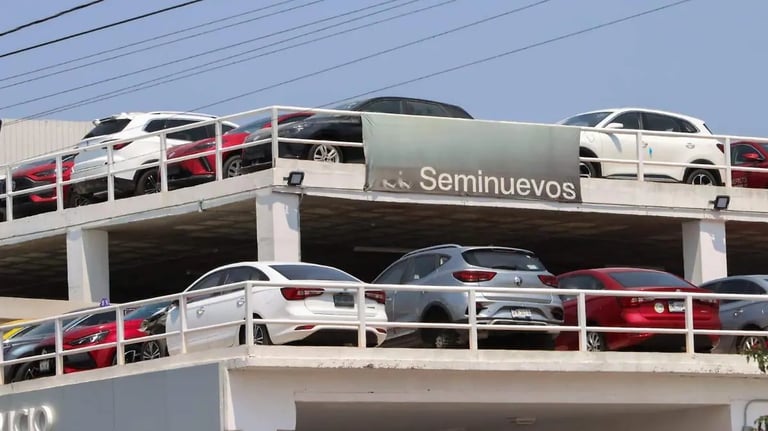 Multi-level parking structure with Seminuevos sign displaying stacked used vehicles