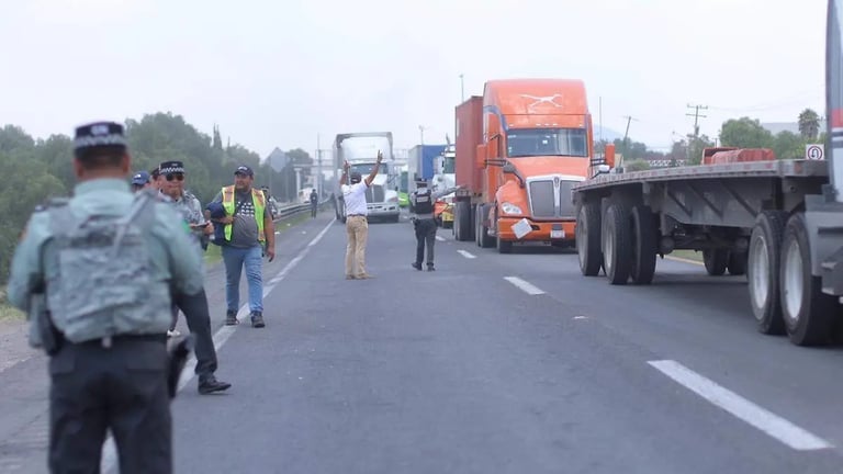 Emergency responders on highway with orange semi-truck and multiple vehicles stopped for incident investigation