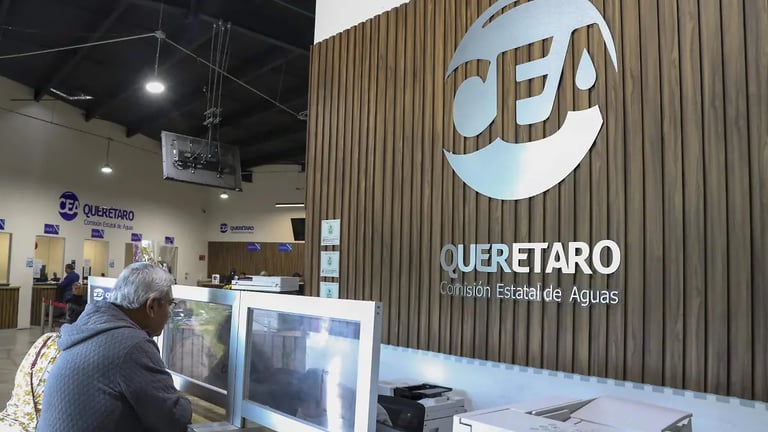 Reception area of CEA Querétaro water authority with staff member at desk and company logo on wooden wall