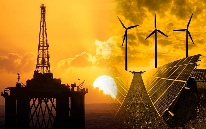Silhouetted oil rig, wind turbines, and solar panels against a golden sunset sky, representing renewable and fossil fuel energy sources.