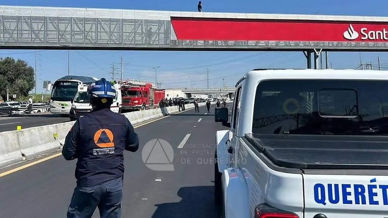 Emergency responder in protective gear directing traffic on highway with police and fire vehicles visible